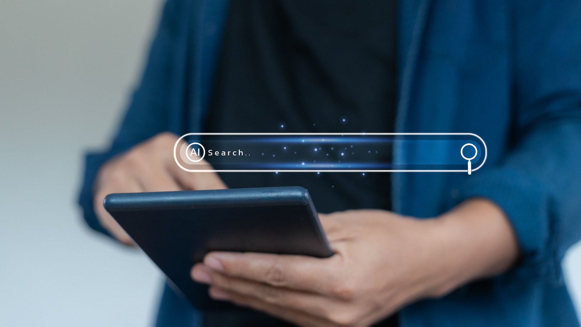 Close-up of hands using a tablet with an AI search bar interface, representing artificial intelligence, smart search engine, and digital information technology.